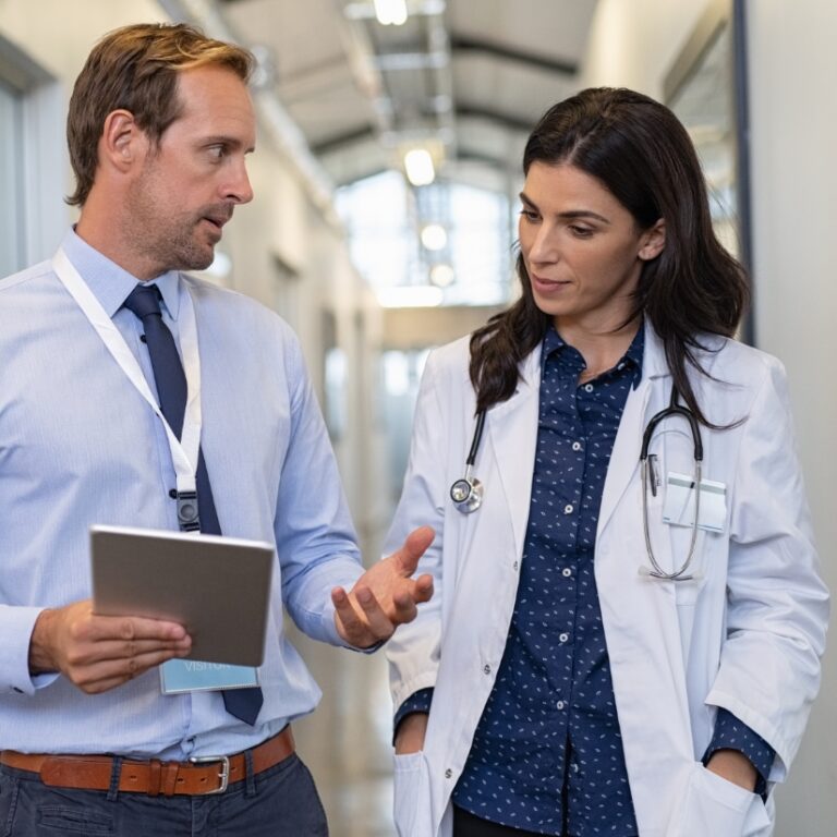 M&A-Mitarbeiter zeigt Ärztin bzw. Kundin im Bereich Healthcare etwas auf dem Tablet